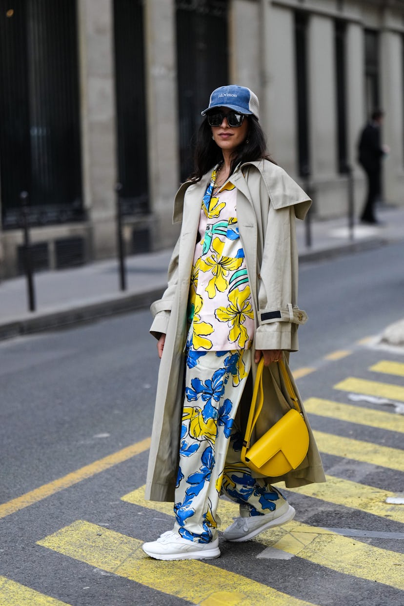 PARIS, FRANCE - MARCH 01: A guest wears a navy blue denim and white mesh cap with white embroidered ...