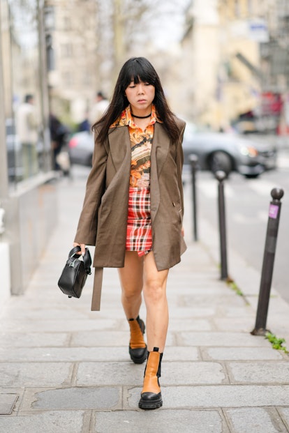 PARIS, FRANCE - MARCH 02: A guest wears a black necklace, a yellow / orange / beige print pattern sh...