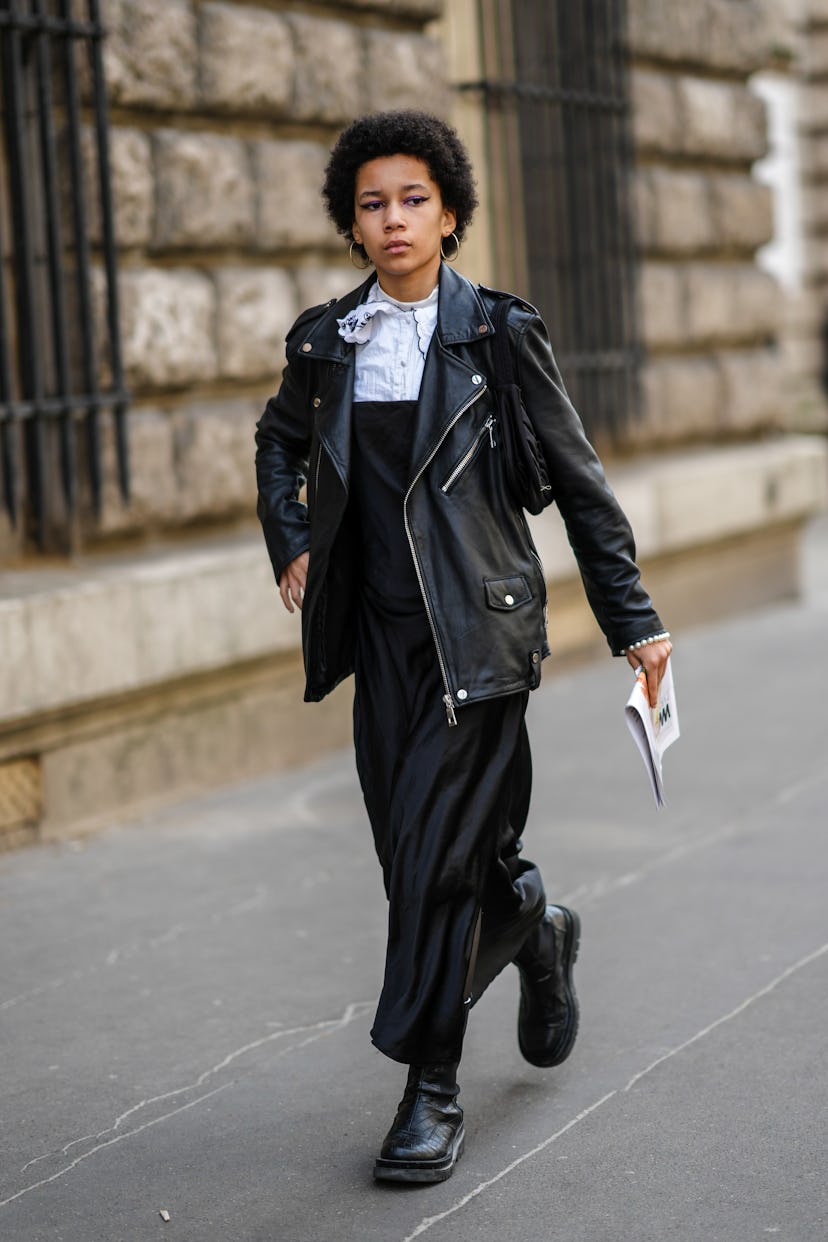 PARIS, FRANCE - MARCH 05: A guest wears gold earrings, a white blouse / shirt, a black shiny leather...