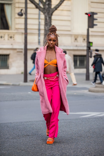 PARIS, FRANCE - MARCH 02: A guest is seen wearing orange cropped top, pink teddy coat, micro bag, pi...