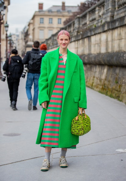 PARIS, FRANCE - MARCH 01: Marianne Theodorsen wearing green coat, Louis Vuitton bag, striped dress, ...