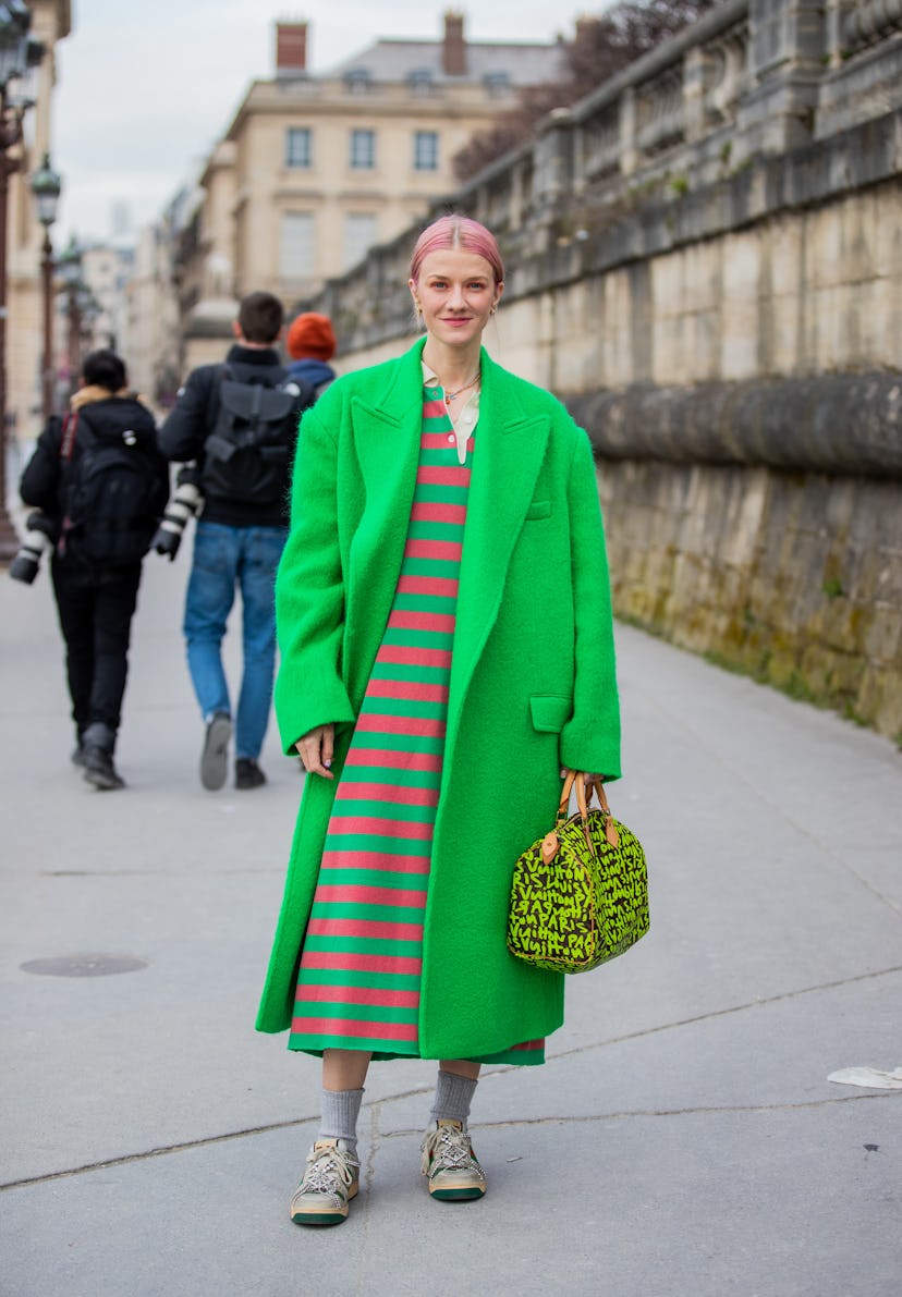 PARIS, FRANCE - MARCH 01: Marianne Theodorsen wearing green coat, Louis Vuitton bag, striped dress, ...