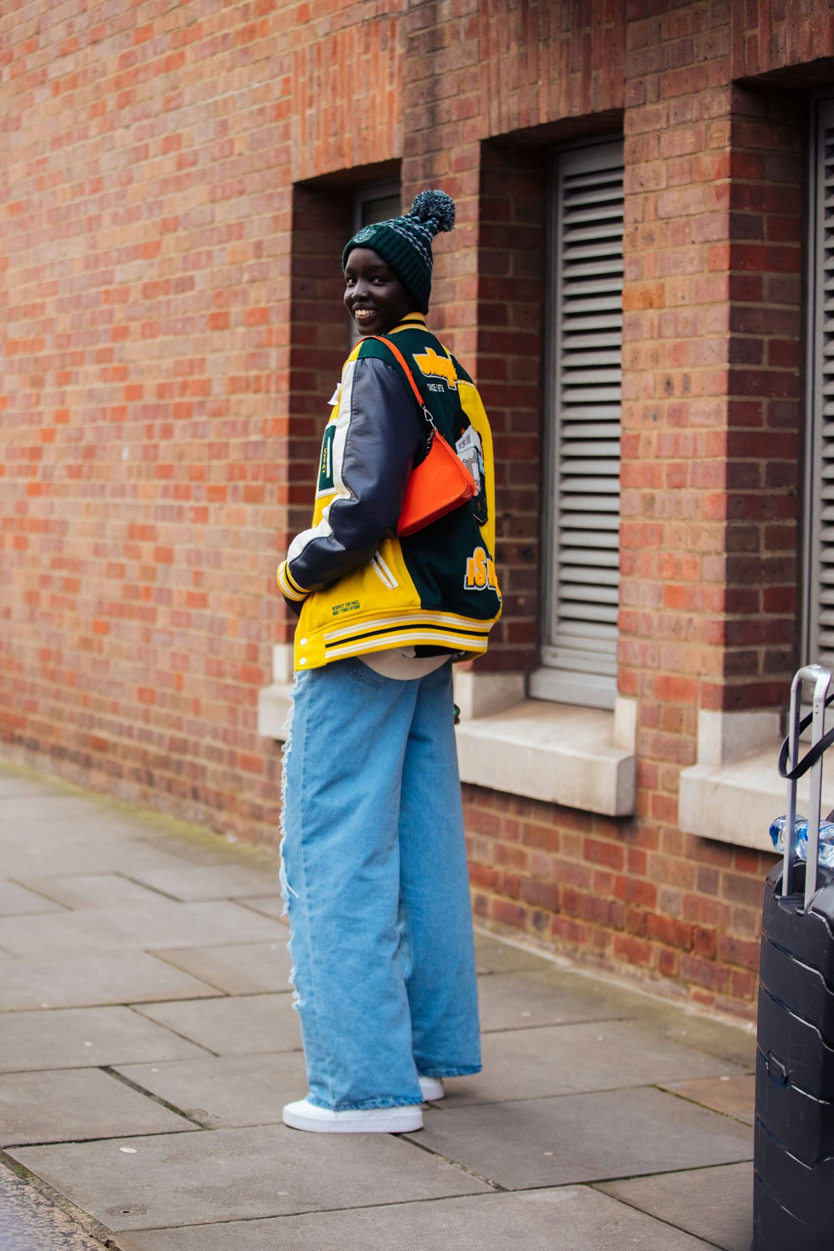 LONDON, ENGLAND - FEBRUARY 21: South Sudanese model Akuol Deng Atem wears a green pom pom hat, yello...