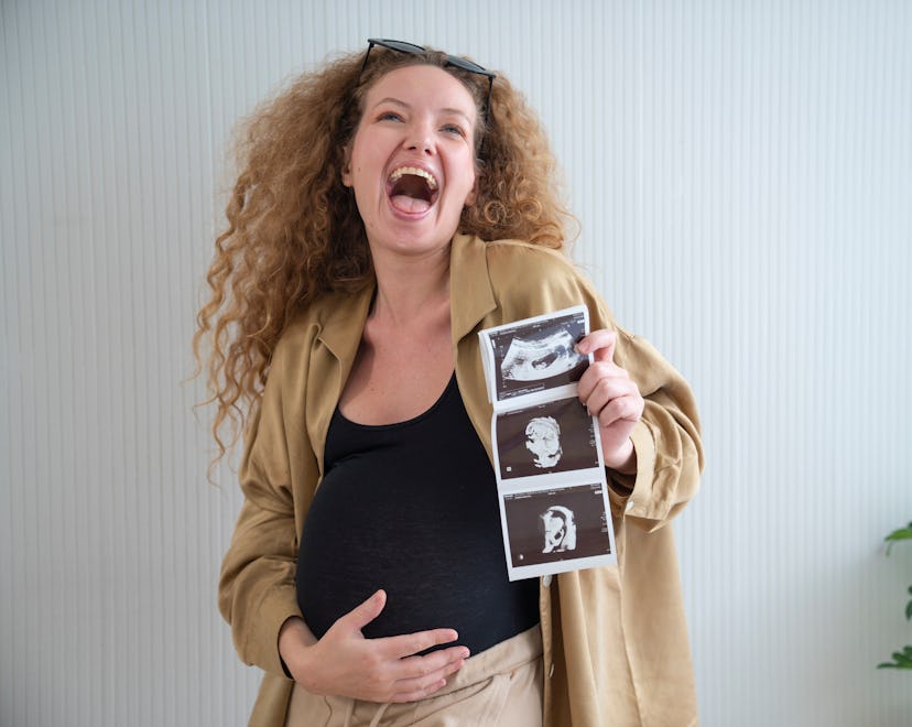 woman holding ultrasound pic sharing pregnancy news, sharing with a riddle is a fun way to announce