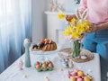 Woman decorating Easter table with a sweet Easter bunny and spring flower bouquet.
