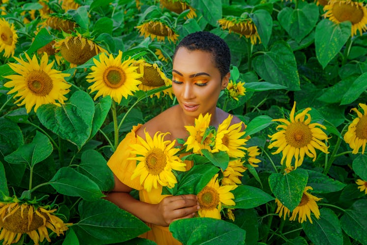 Young woman lounging in a field of sunflowers, absorbing the meaning of the May 2, 2022 weekly horos...