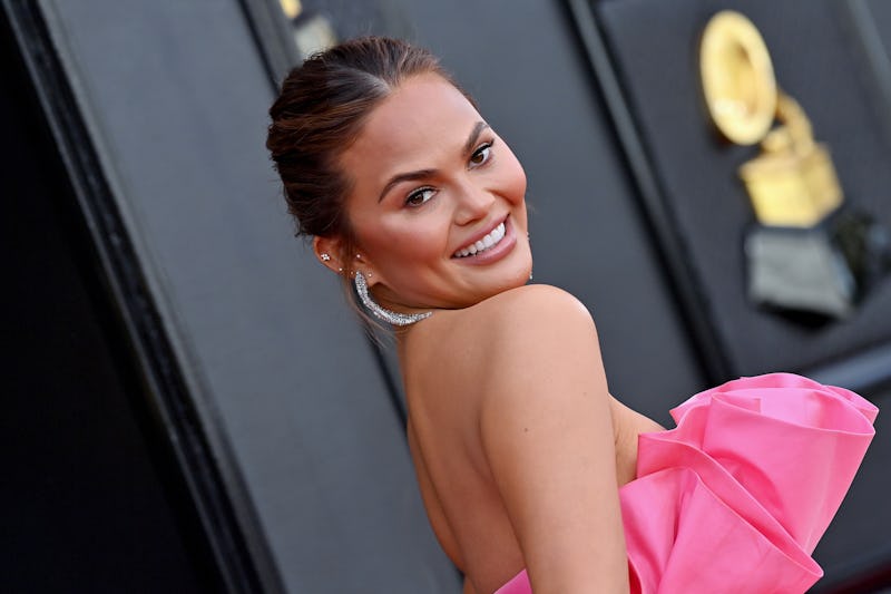 Chrissy Teigen attends the 2022 GRAMMY Awards in pink ruffled dress