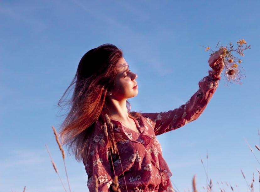 young woman holding a bouquet of flowers closes her eyes as she thinks about the april 2022 Black Mo...