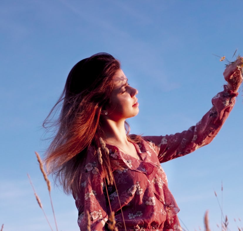 young woman holding a bouquet of flowers closes her eyes as she thinks about the april 2022 Black Mo...