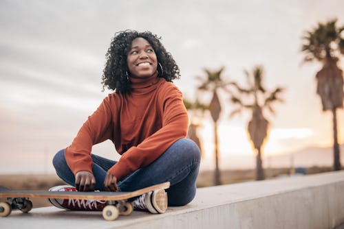 Young women with skateboard sitting neat the beach during the sunset. Here’s your daily horoscope fo...