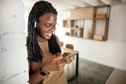 Woman is standing in her home office and using her mobile phone