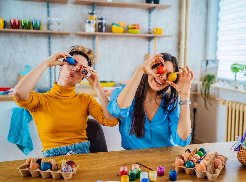 Two women hold up Easter eggs and plan Easter games for kids and adults. 