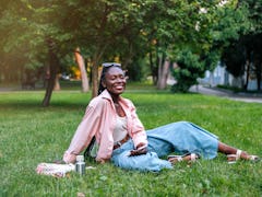 Young woman, who has an Aries rising sign, sitting in a park.