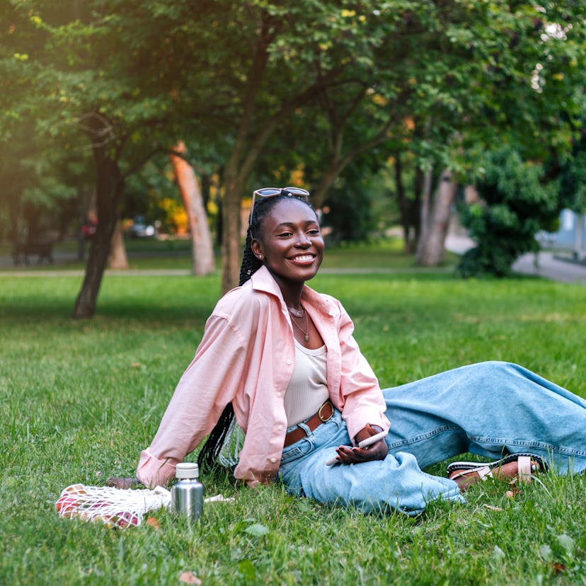Young woman, who has an Aries rising sign, sitting in a park.
