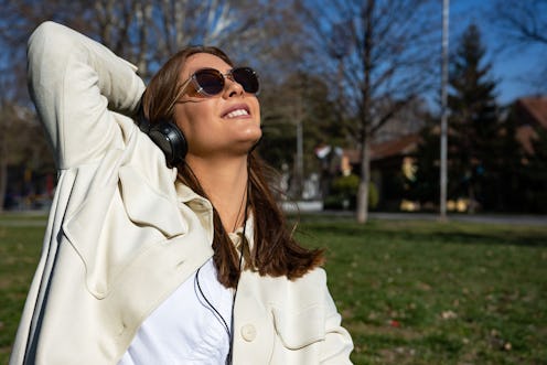 Beautiful young woman listening to music on headphones. Happy in sunglasses