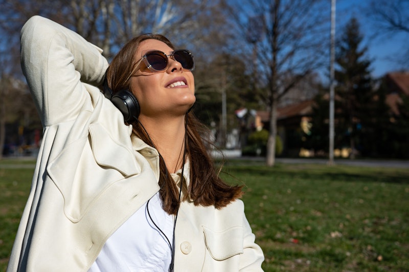 Beautiful young woman listening to music on headphones. Happy in sunglasses