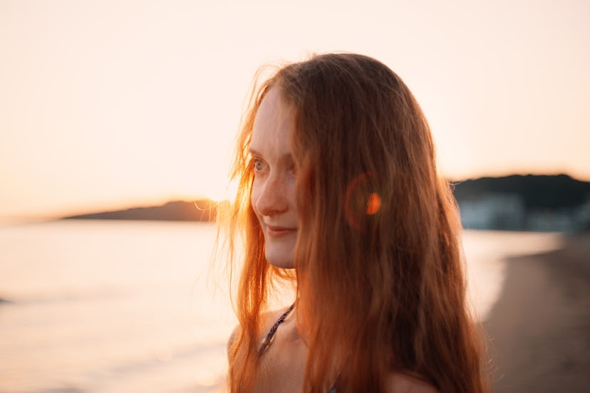 Side view portrait of cheerful redhead woman at sunset on beach in Montenegro Ulcinj, Tranquil scene...
