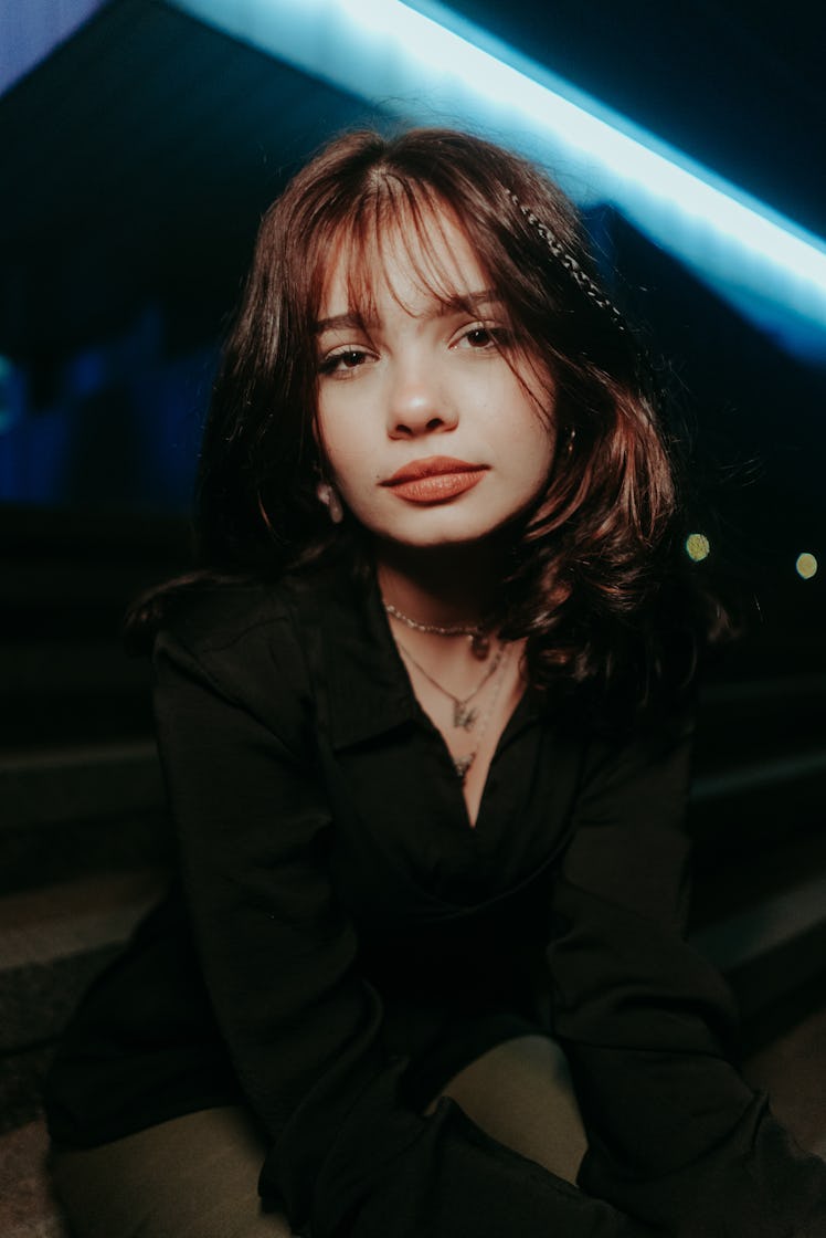 Young woman basking in the city lights at night, knowing her unlucky zodiac sign will have the worst...