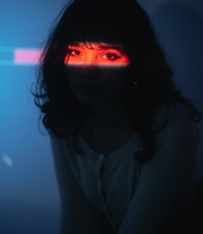 Young woman posing under neon lights, knowing Mercury retrograde spring 2022 will affect her zodiac ...