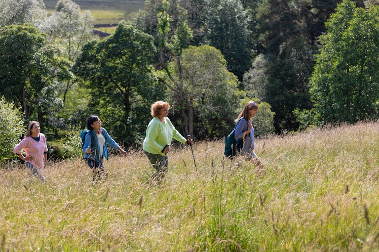 Side view of senior women hiking together in Northumberland in a wilderness area talking and enjoyin...