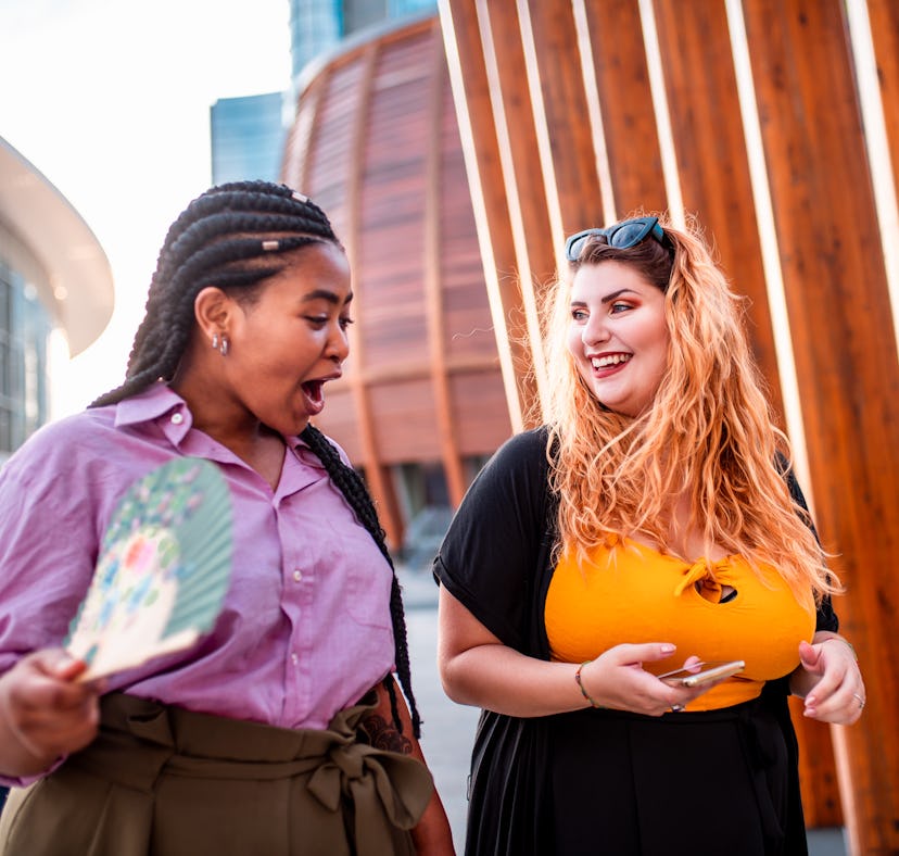 Two friends laugh at inappropriate group chat names together.