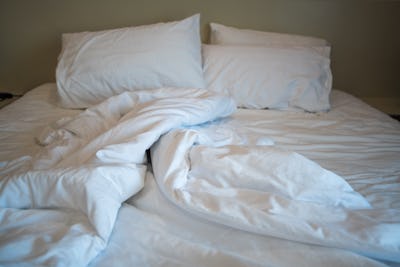 A close-up view of messy bed with comforter and pillows an hotel bedroom