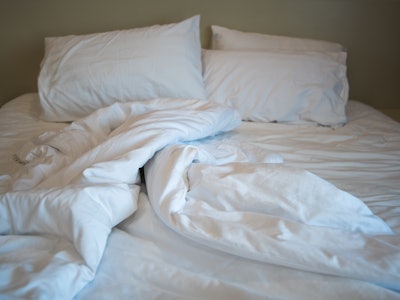 A close-up view of messy bed with comforter and pillows an hotel bedroom