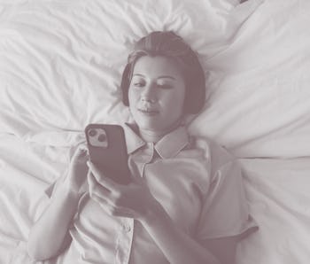 Above shot of an Asian female with her headphones on, texting on her cell phone device. She looks pe...