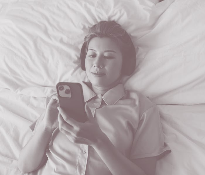 Above shot of an Asian female with her headphones on, texting on her cell phone device. She looks pe...