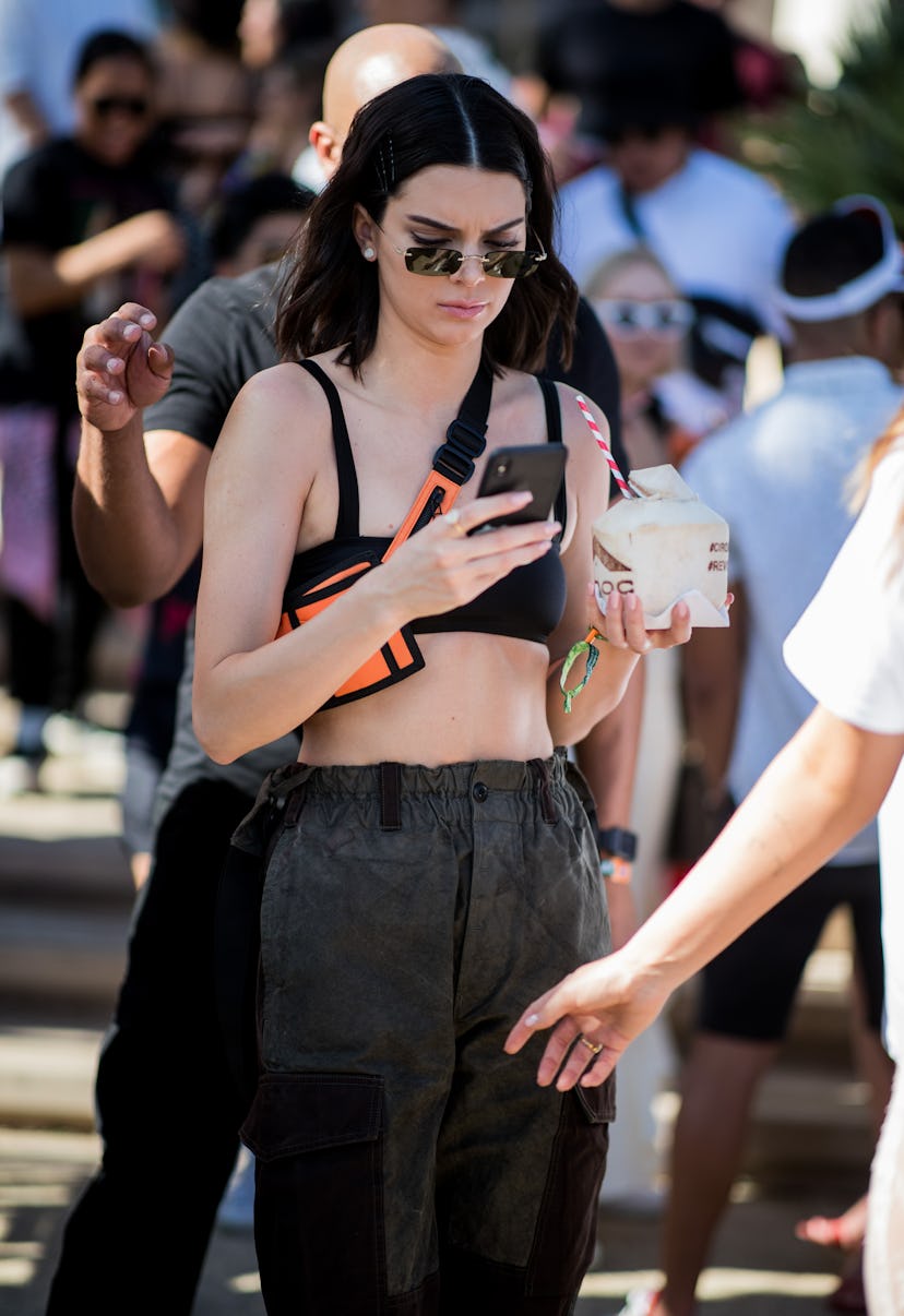Kendall Jenner is seen at Revolve Festival on April 14, 2018 wearing cropped top, belt bag, and carg…