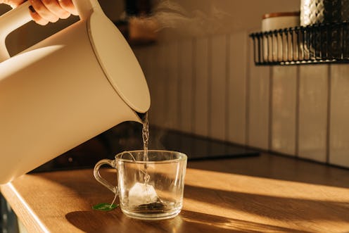 Hot steaming black tea in a cup on a rustic background