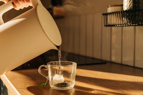 Hot steaming black tea in a cup on a rustic background