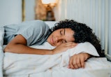 A woman lies asleep in bed. Experts recommend the best products for falling asleep.