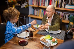 A modern Jewish American family celebrates Passover together, dipping the karpas (parsley) in salt w...