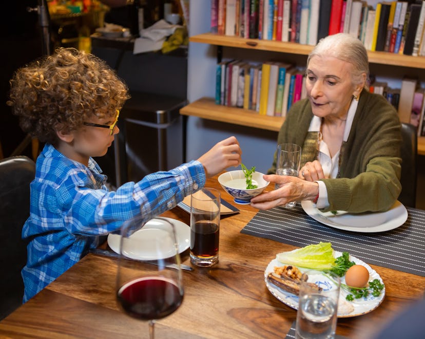 A modern Jewish American family celebrates Passover together, dipping the karpas (parsley) in salt w...