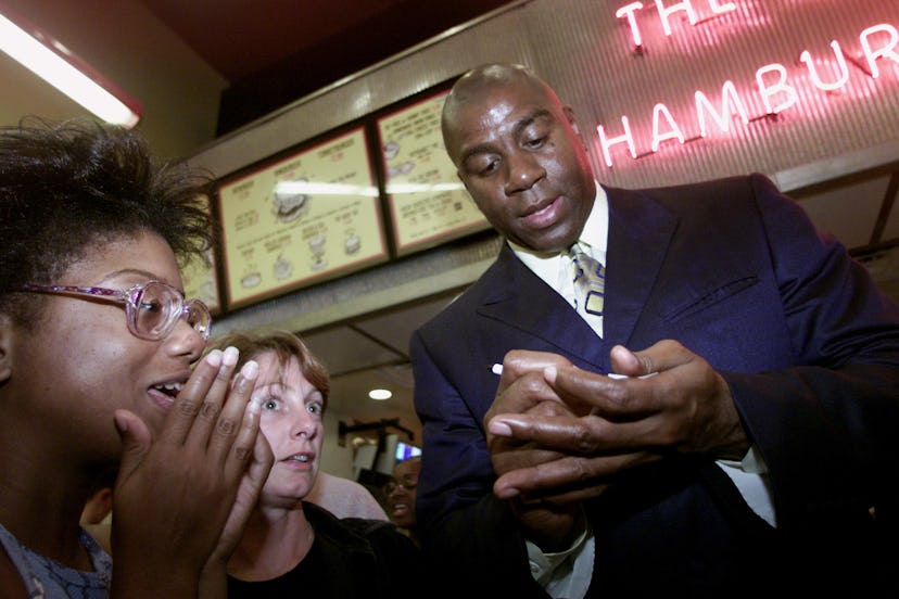 Magic Johnson signs autographs at the public announcement that an investment group he leads will acq...