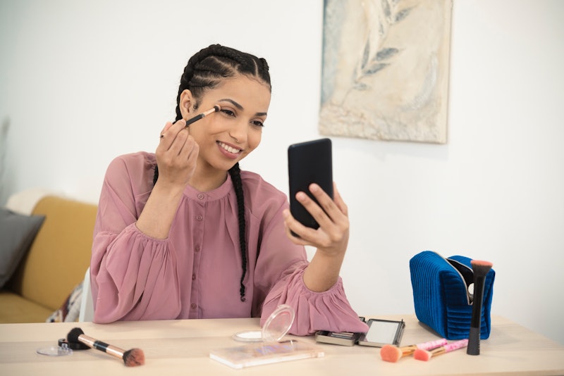 Portrait of a beautiful, young woman putting makeup on her face