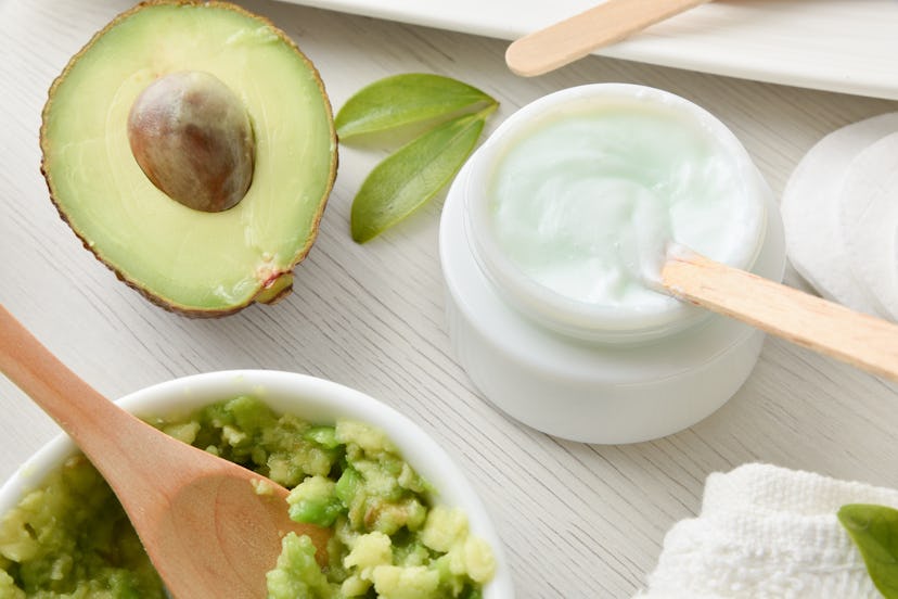 Detail of preparation of natural cosmetics with avocado extract with fruit and cream and tools on wo...