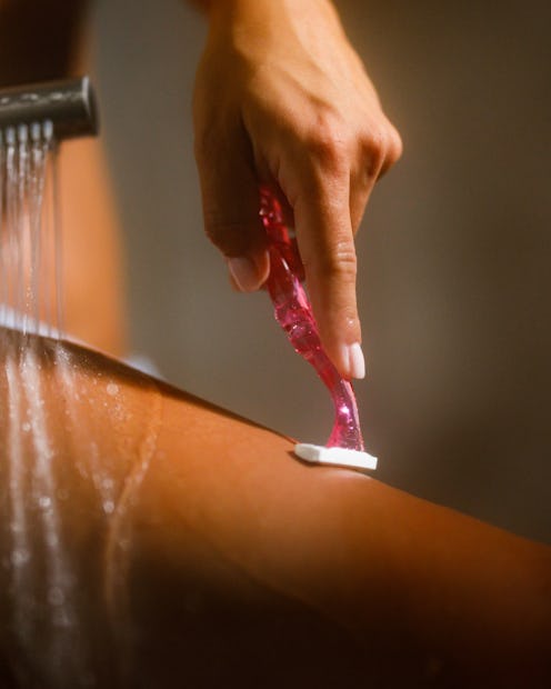 Close up of unrecognizable woman shaving her leg during a shower in the bathroom.