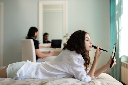 woman putting on make up while laying on bed