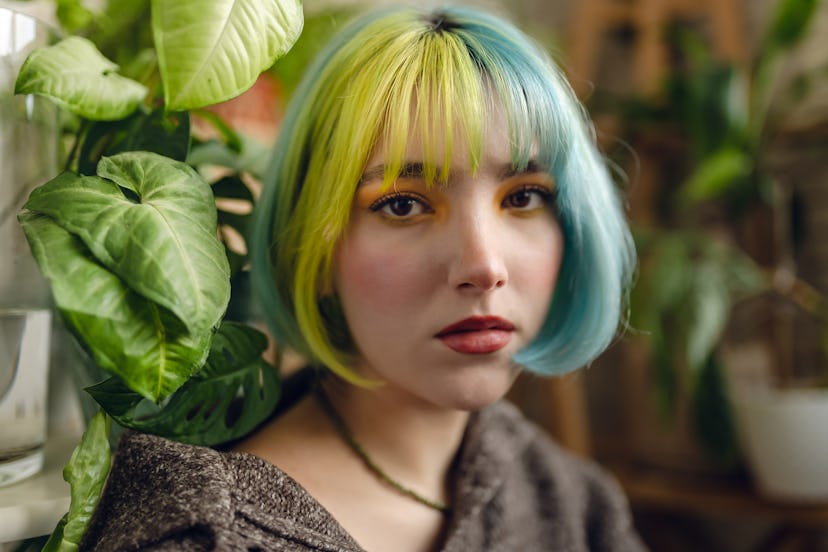 Portrait of beautiful young woman with colorful hair and make-up together with plants