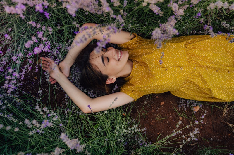 Photo of a smiling young woman lying in lavender; enjoying the beautiful and peaceful weekend getawa...