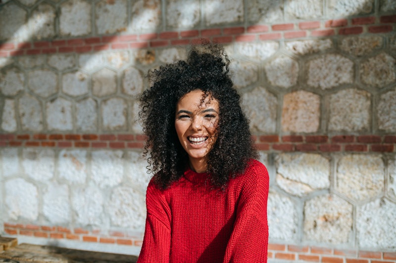 Portrait of woman with afro hair looking at camera outdoors.