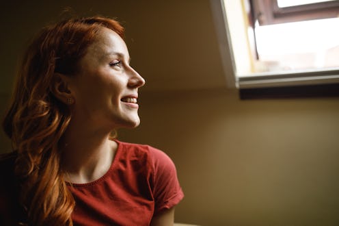 Copy space shot of beautiful young redhead relaxing after a long day, looking out the slanted window...