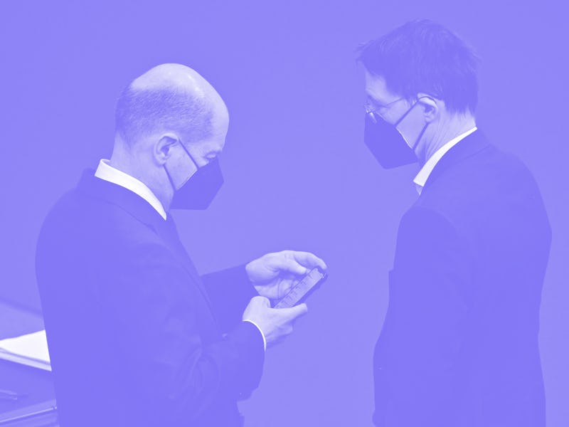 German Chancellor Olaf Scholz (L) checks his phone as he speaks with German Health Minister Karl Lau...