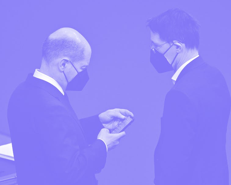 German Chancellor Olaf Scholz (L) checks his phone as he speaks with German Health Minister Karl Lau...