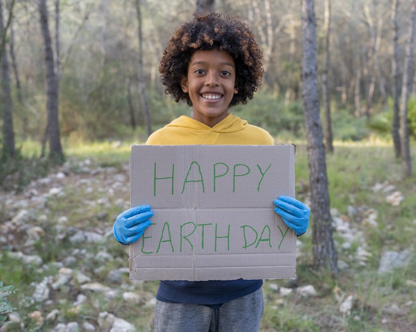 A black boy holds up a "Happy Earth Day" sign