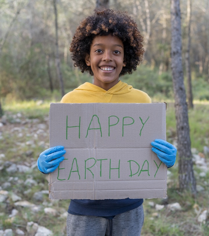 A black boy holds up a "Happy Earth Day" sign