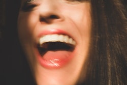 Closeup of woman's face and mouth laughing. Candid woman has her mouth open with happiness and laugh...