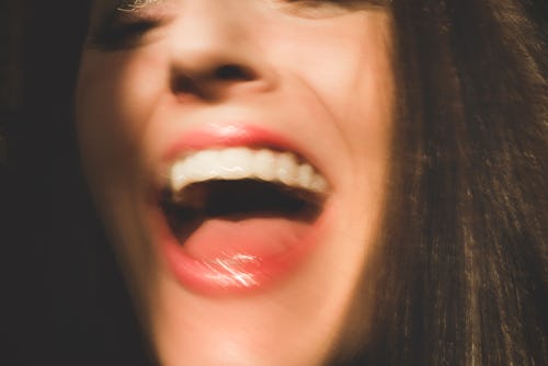 Closeup of woman's face and mouth laughing. Candid woman has her mouth open with happiness and laugh...
